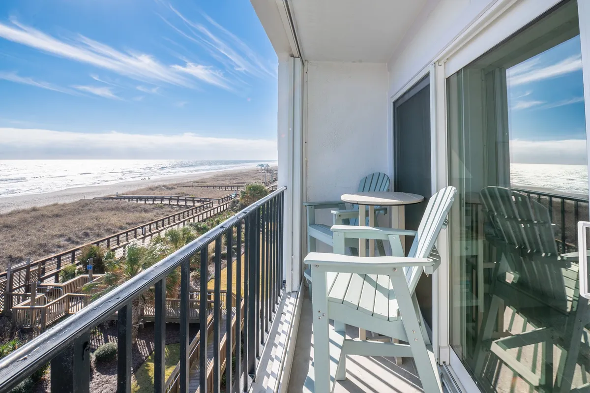 A private balcony furnished with two chairs and a small table overlooks a breathtaking ocean view. The scene exudes tranquility, inviting guests to enjoy morning coffee or evening cocktails while taking in the sights and sounds of the sea.
