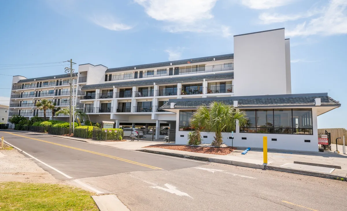This image shows the exterior of Cabana Suites, featuring the building’s facade, palm trees, balconies, and a sidewalk. The inviting outdoor setting hints at the lively, walkable community atmosphere and social possibilities just outside the doorstep. The balconies suggest opportunities for guests to enjoy ocean breezes or sunset cocktails before heading out for the evening.