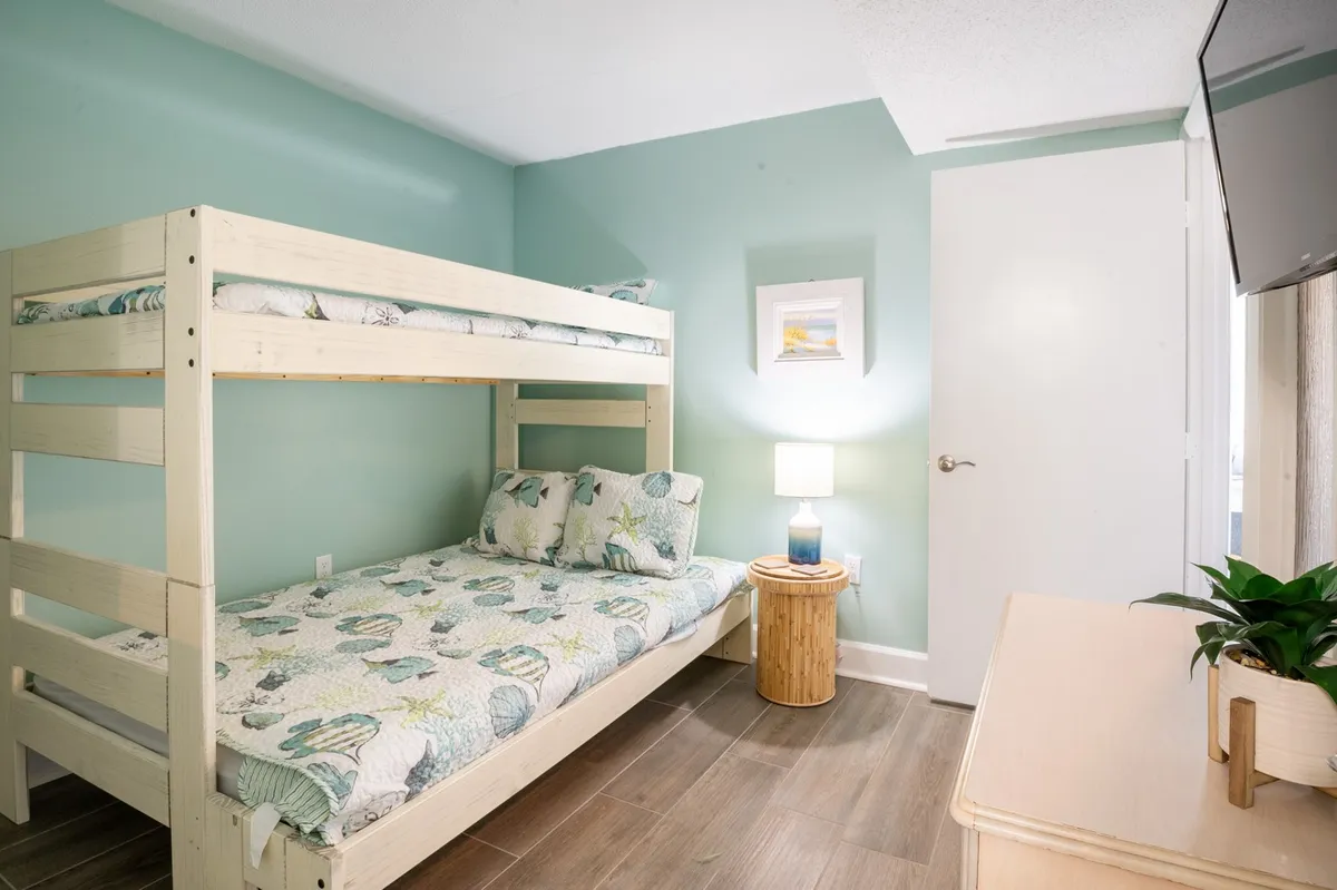 A cozy guest bedroom with a twin-over-full bunk bed, a side table, and a gentle, playful decor. Soft lighting creates an inviting atmosphere, making it ideal for kids or close friends.